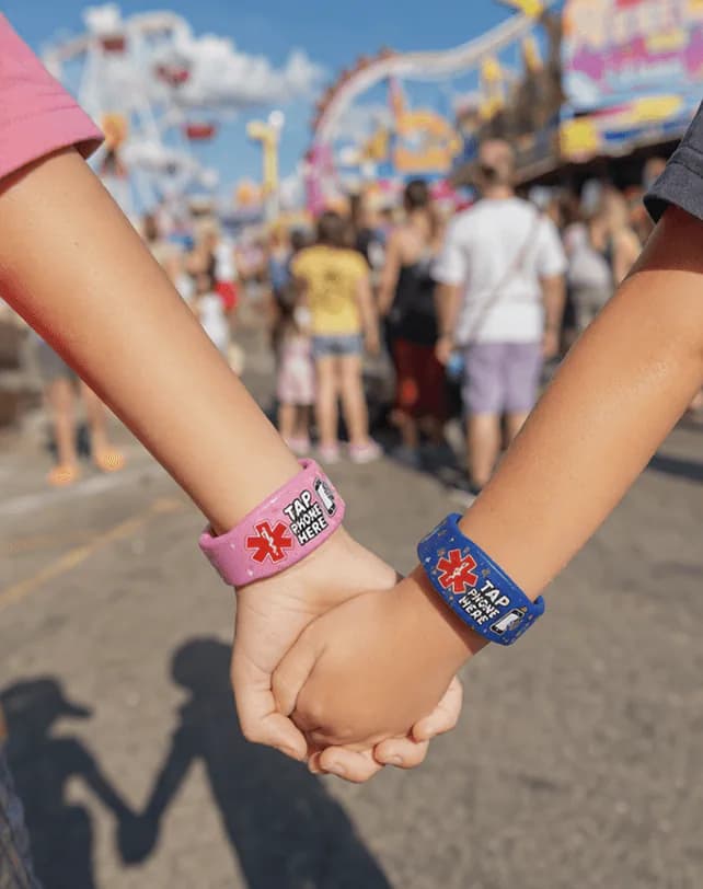 Two children holding hands at a fair, one in each band design