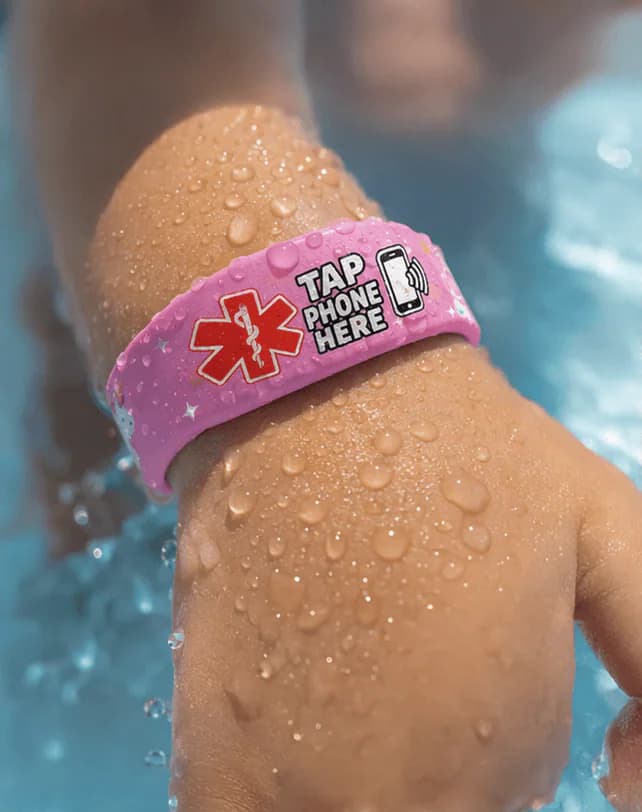 A wet wrist wearing the Unicorn band at the pool